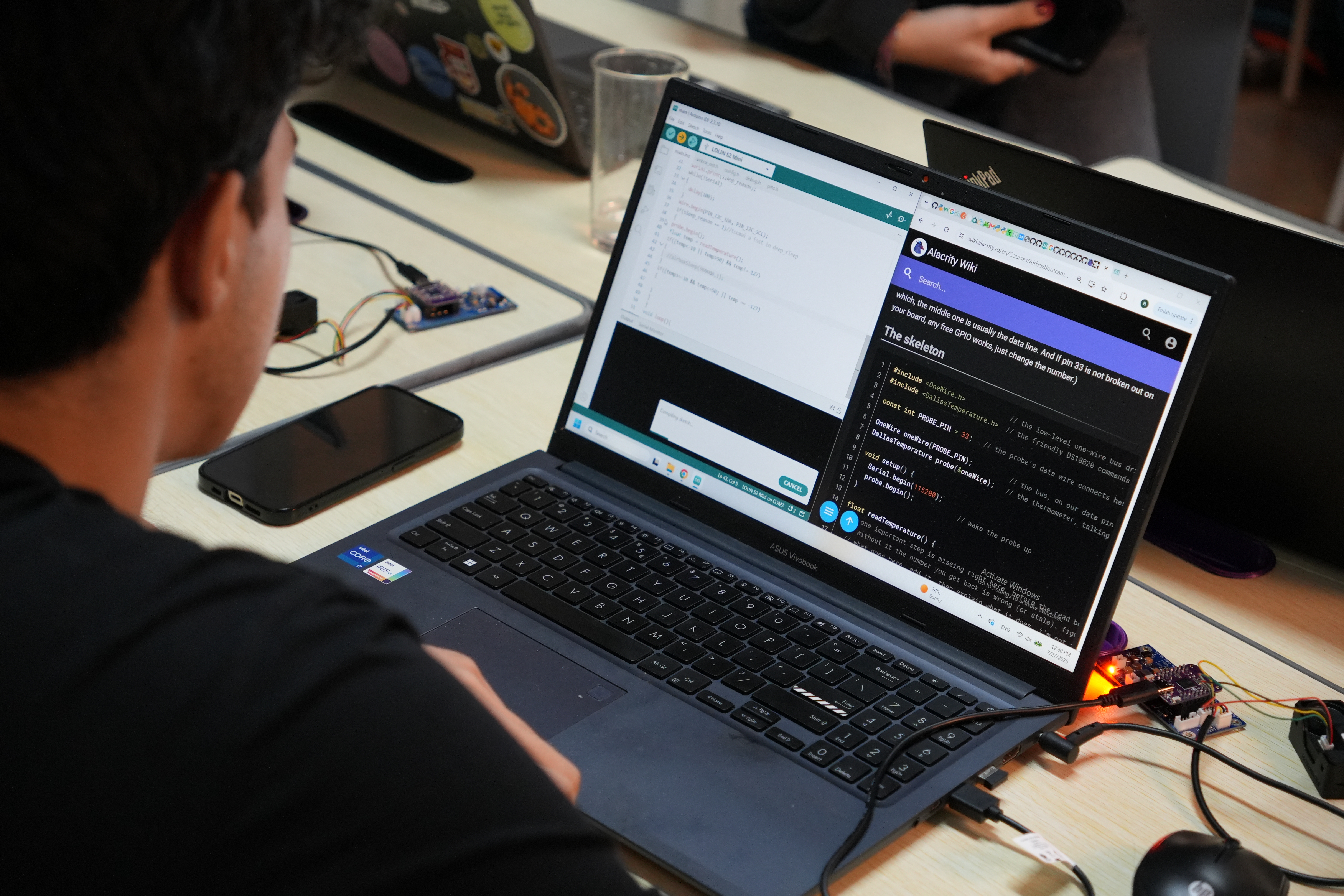 Student programming on a laptop connected to an electronics prototype