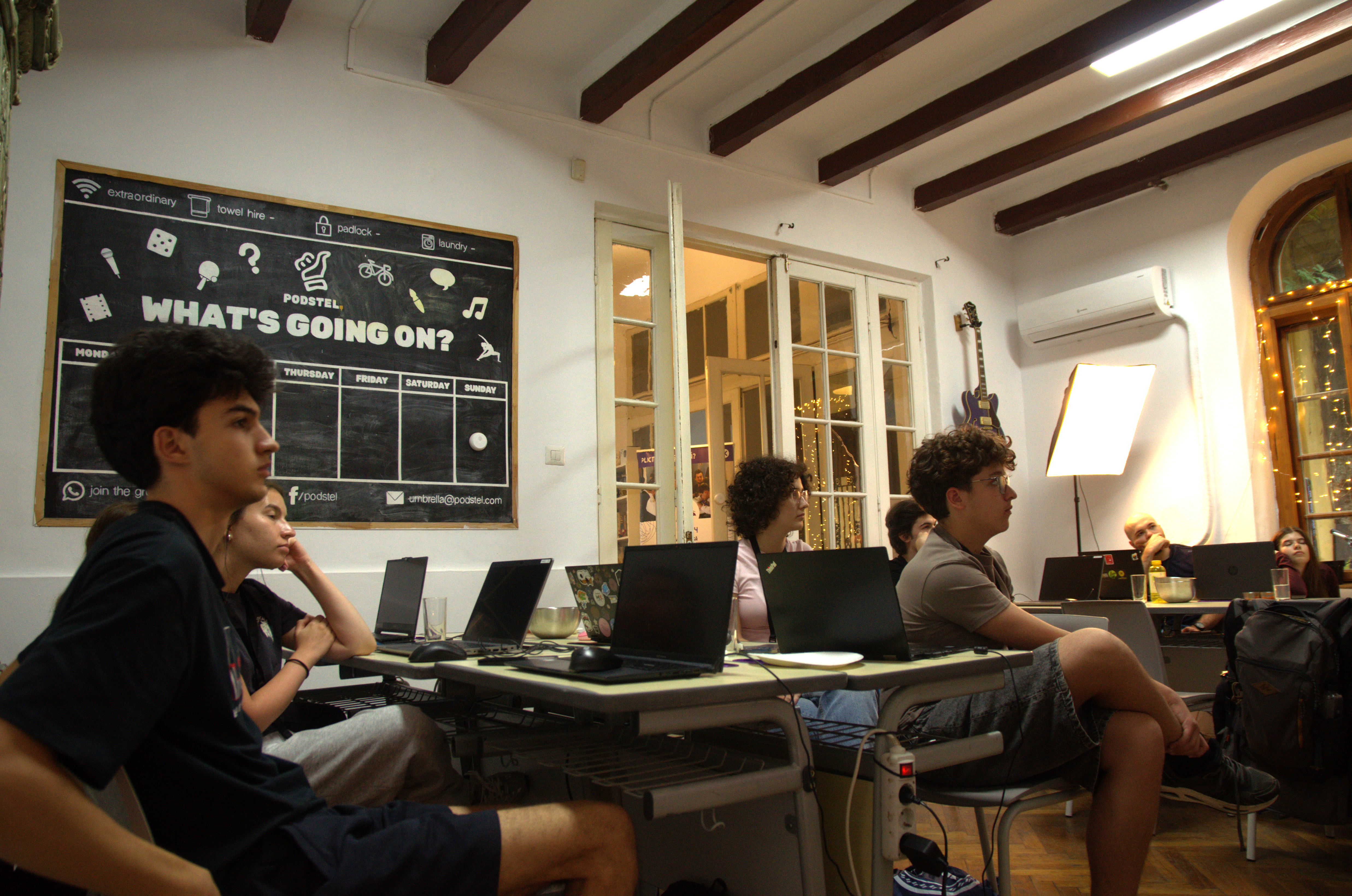 Students at laptops in the Alacrity classroom with a chalkboard on the wall