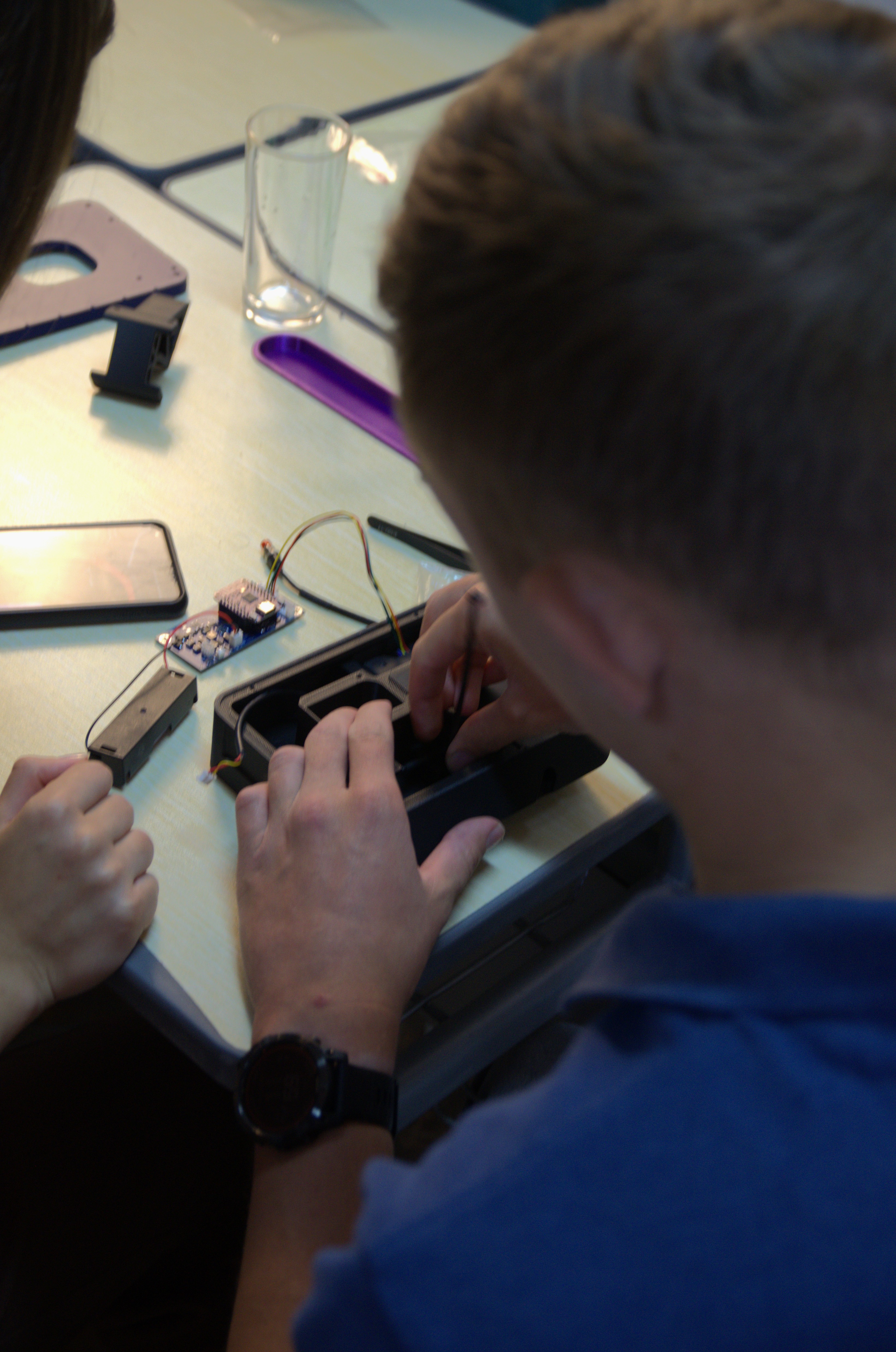 Student assembling electronics on a desk, seen over the shoulder