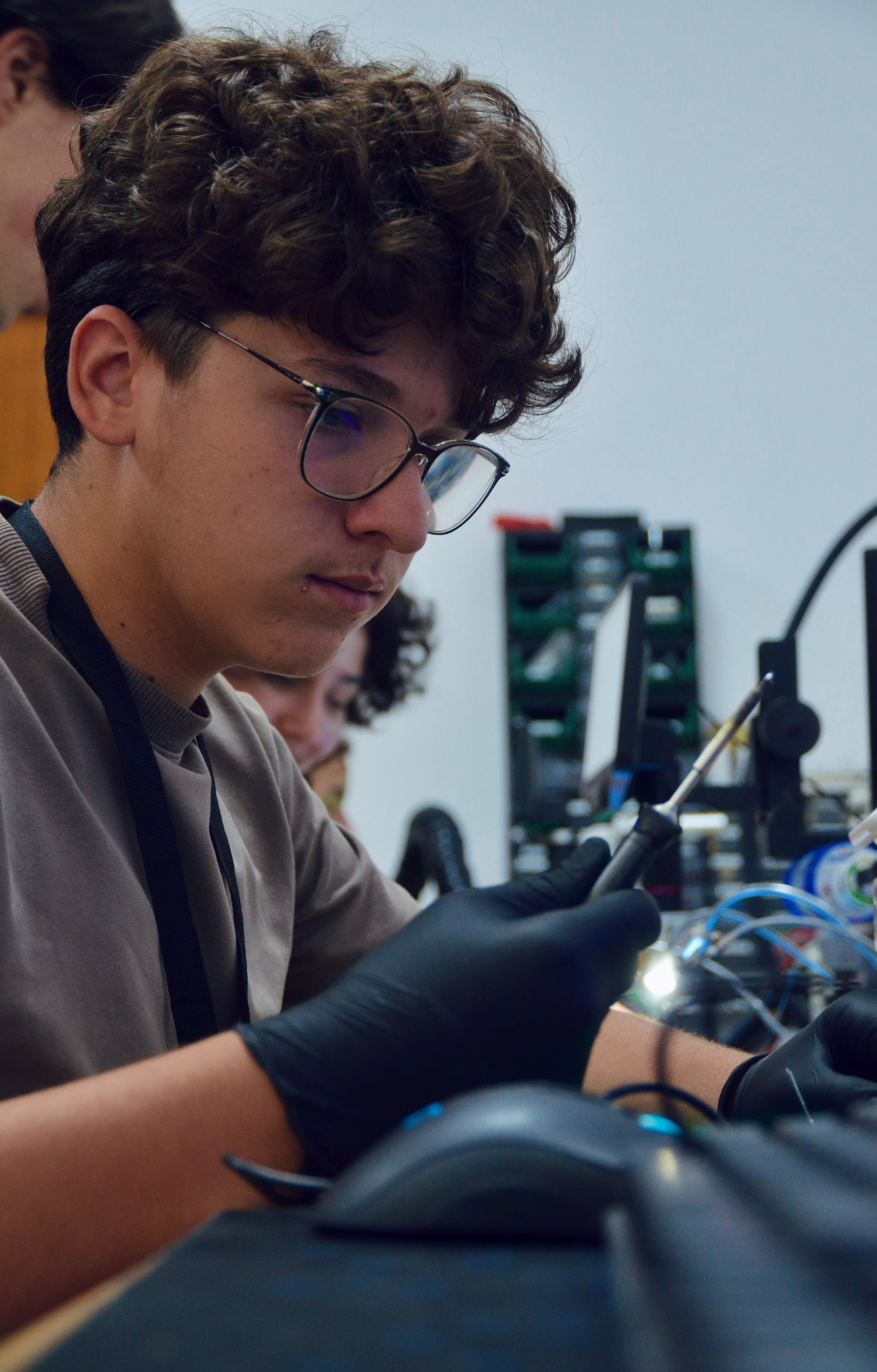 Student in black gloves working with tweezers at an electronics workbench