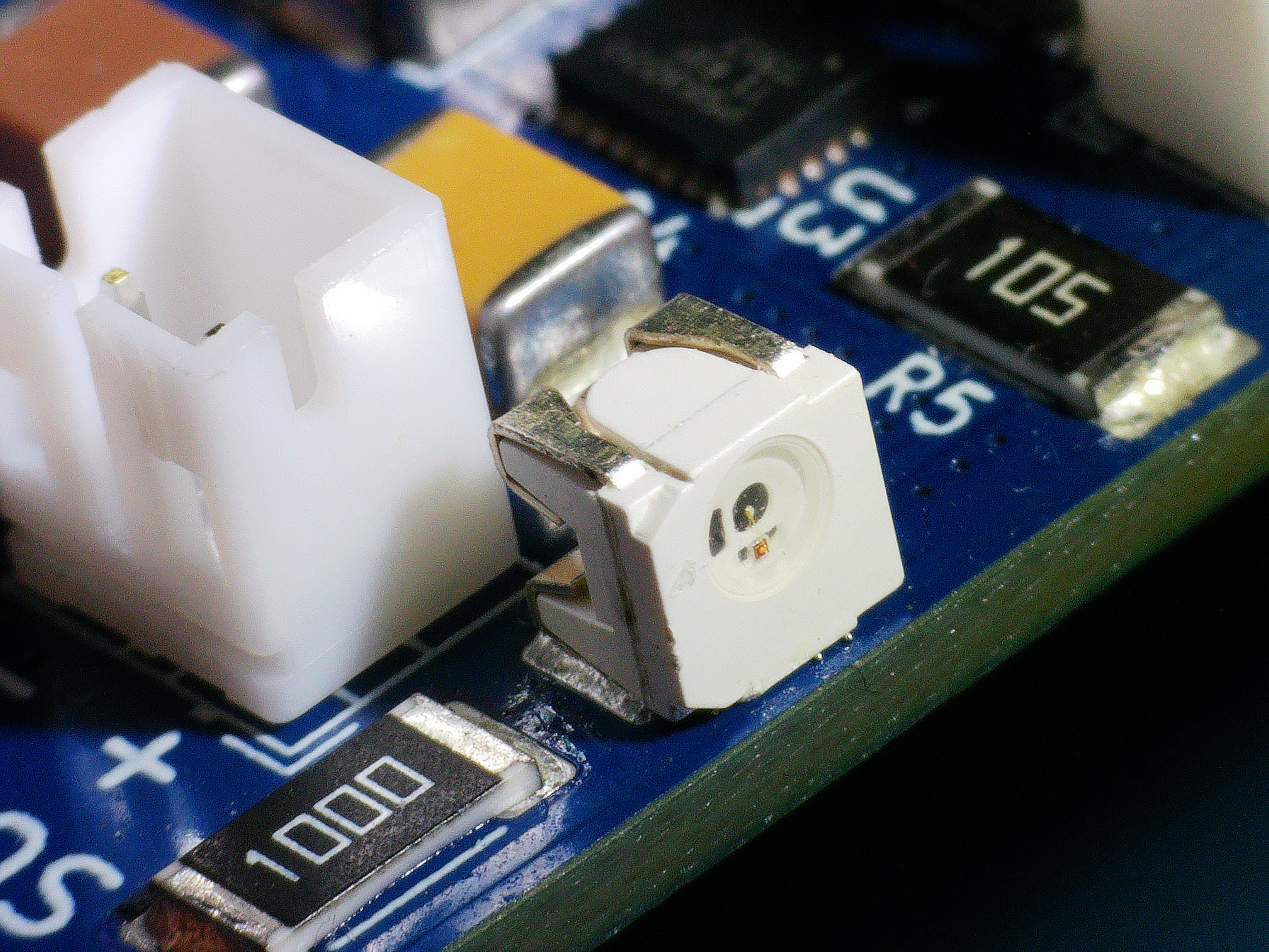 Close-up of an SMD LED, connector and resistors soldered on a blue AirBox PCB